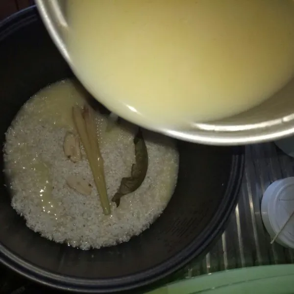 Tuang santan cair pada beras, ukur air santan satu ruas  jari di atas beras. Ukuran untuk nasi agak pera tetapi tidak keras. Jika mau pulen bisa ditambah. Aduk rata