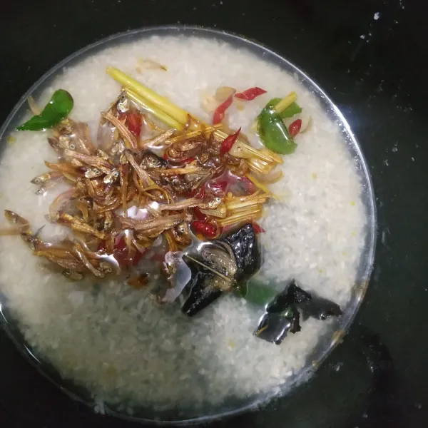 Cuci beras lalu masukkan ke dalam rice cooker dan beri air seperti takaran memasak nasi biasa. Masukkan bumbu tumisan dan teri goreng. Tunggu hingga matang