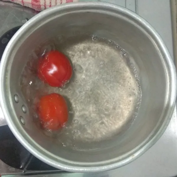 Masak air hingga mendidih, masukan tomat, rebus hingga kulit tomat mulai terkelupas, matikan api