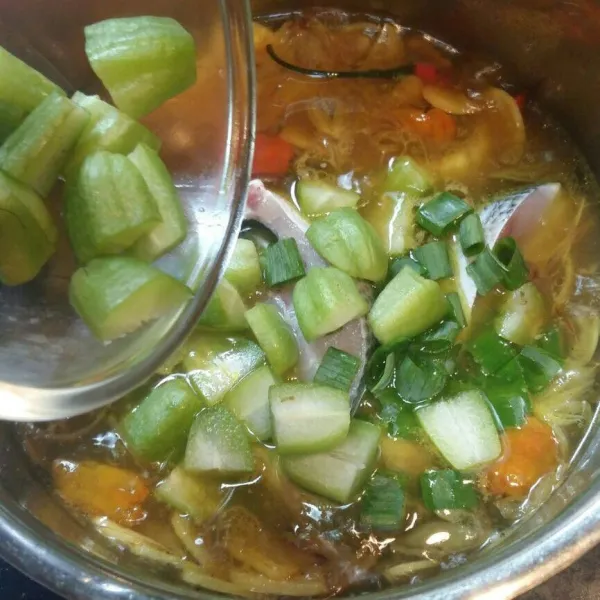 Lalu masukkan daun bawang rajang dan belimbing sayur. Masak hingga ikan matang