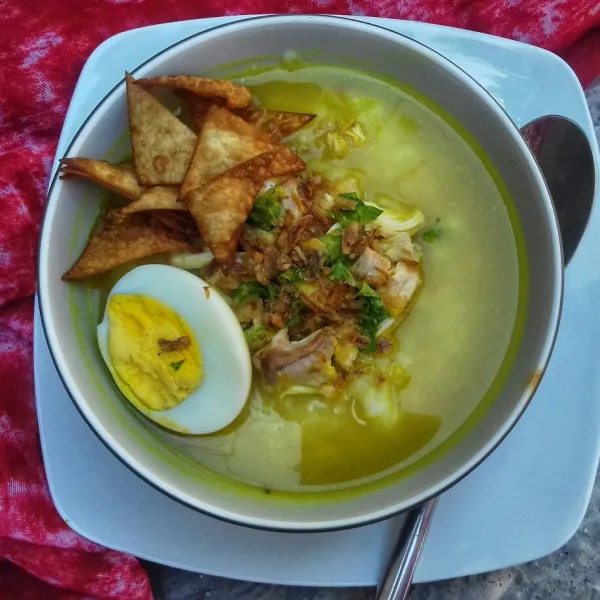 Penyajian, letakkan bubur dalam mangkok, beri suiran ayam goreng, telur rebus dan pelengkap yang lain, siram dengan kuah kuning tadi. Siap disajikan