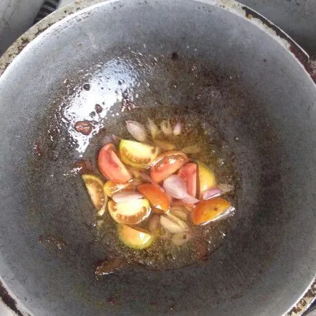 Panaskan sedikit minyak di wajan, lalu tumis bawang merah dan tomat hingga layu.
