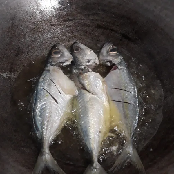 Goreng ikan di minyak panas, masak ikan sampai kuning keemasan.