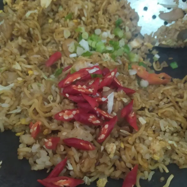 Terakhir tambahkan irisan cabai dan daun bawang, aduk, nasi goreng siap disajikan