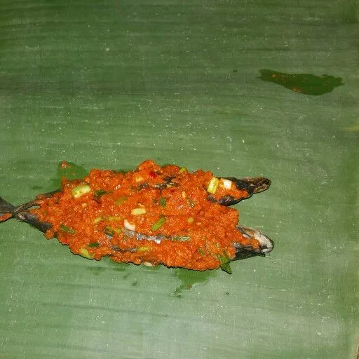 Siapkan selembar daun pisang. Beri dua ekor ikan beserta bumbunya. Bungkus layaknya pepes. Semat dengan tusuk gigi