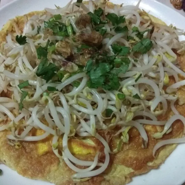 Tata telur dadar di atas piring, tambahkan toge, seledri dan bawang merah goreng. Tuangkan bumbu kacangnya.