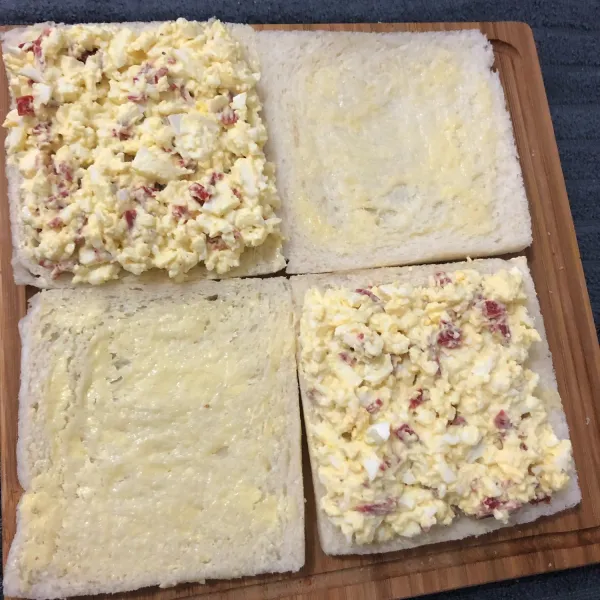 Tuang telur ke atas roti yang telah diolesi mentega, lalu ratakan dan potong menjadi dua bagian. Sajikan.