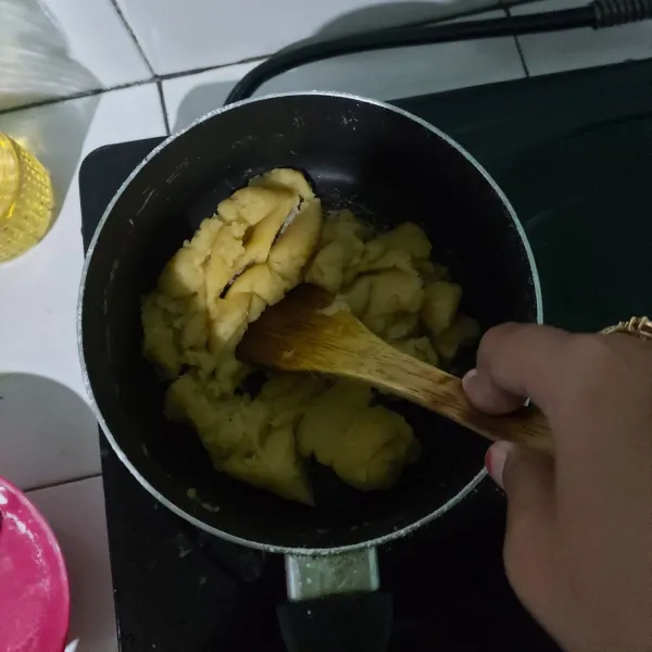 Matikan kompor kemudian masukkan tepung ke dalam panci, aduk-aduk sampai semua tercampur rata. Nyalakan kompor dengan api kecil masak kembali sambil diaduk-aduk kurang lebih seama 1-2 menit. Matikan kompor dan tunggu adonan sampai dingin.