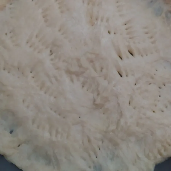 Pipihkan dough pizza di teflon, kemudian tusuk-tusuk dengan garpu.