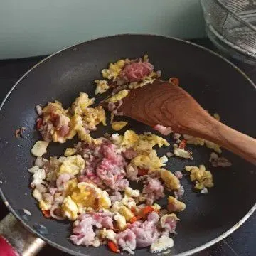 Pinggirkan bawang tadi, orek telur di tempat yang kosong. Setelah agak keras, aduk rata, tambahkan dagingnya kalau sudah aduk lagi biar rata.