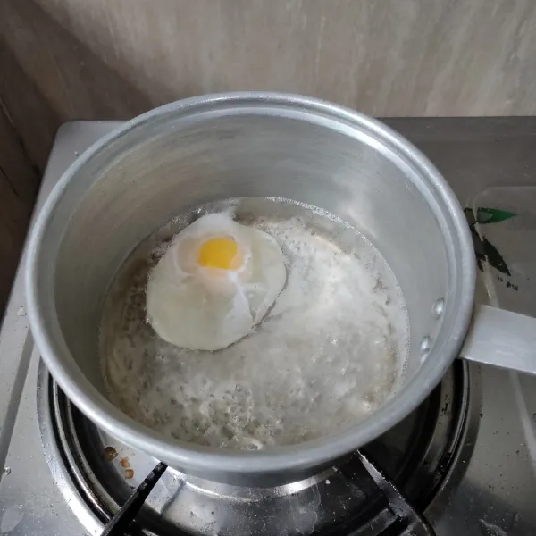 Mulai masak mie: didihkan air, masukkan telur secara perlahan, gunakan api kecil agar kuning telur tidak pecah dan bentuknya tetap cantik.