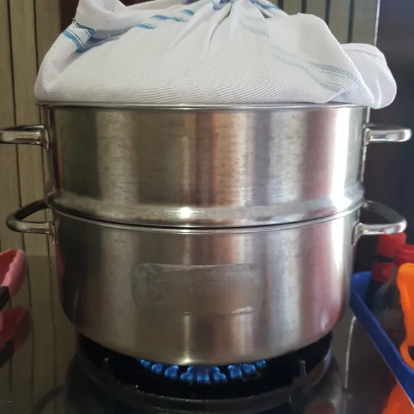 Kukus adonan bolu ke dalam kukusan yang sudah dipanaskan, lalu tutup penutup kukusan dengan kain bersih agar air uap tidak jatuh ke dalam adonan. Kukus dengan api sedang selama 40 menit.