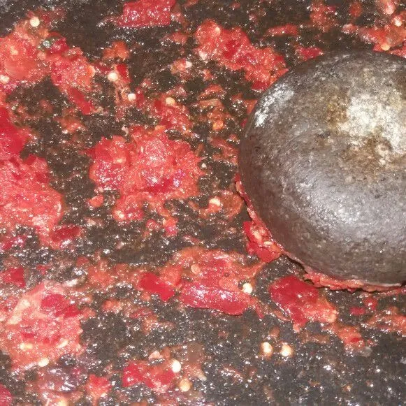 Ulek bawang merah dan bawang putih hingga halus, lalu tambahkan cabai merah dan ulek agak kasar.
