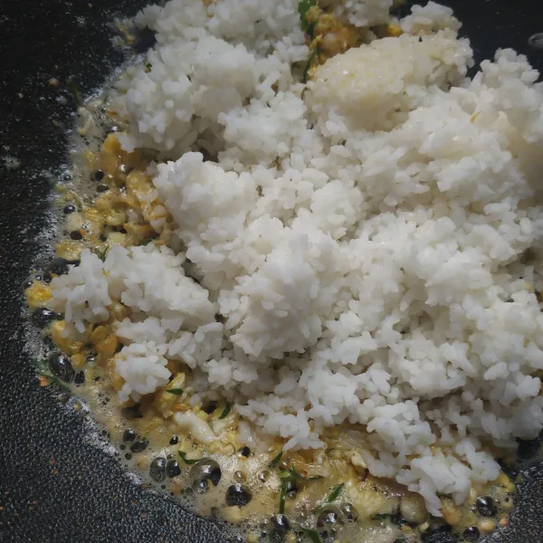 Tambahkan nasi, aduk hingga rata, tambahkan kaldu bubuk, merica, dan daun jeruk utuh, koreksi rasa.