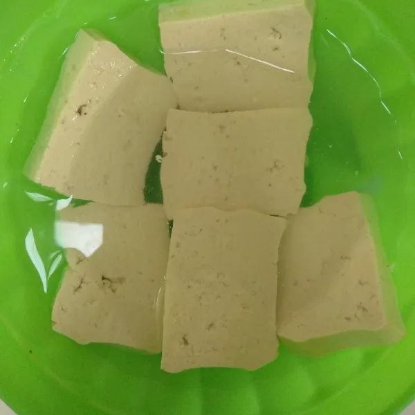 Rendam tahu dalam air yang sudah diberi garam dan penyedap, setelah itu goreng tahu hingga matang.