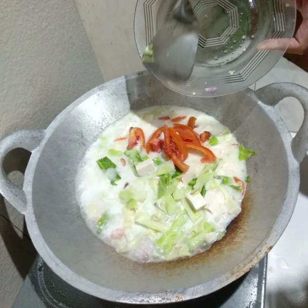Tuangkan kubis, tahu, dan tomat kedalam wajan. Tambahkan pula garam, gula, dan penyedap secukupnya.