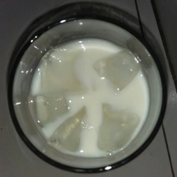 Tuangkan 150 ml susu full cream dan beberapa butir es batu.