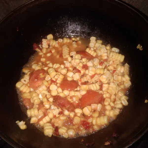Masukkan potongan tomat dan irisan jagung. Masak sampai jagung setengah matang.