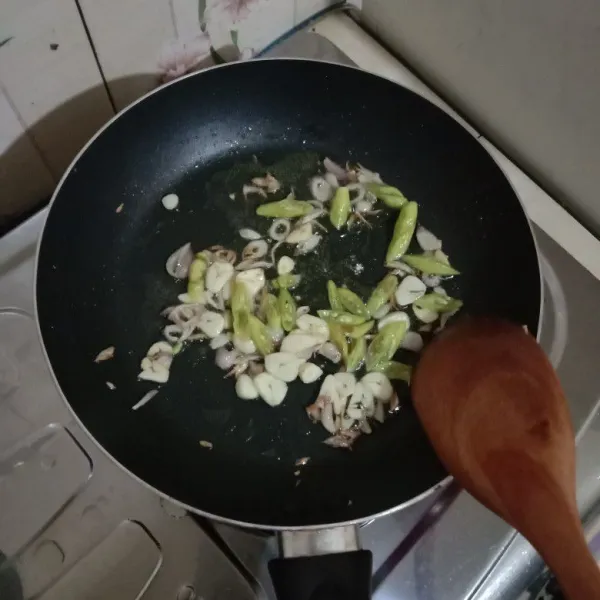 Tumis irisan bawang merah dan bawang putih hingga harum, lalu masukkan irisan cabai, biarkan layu.