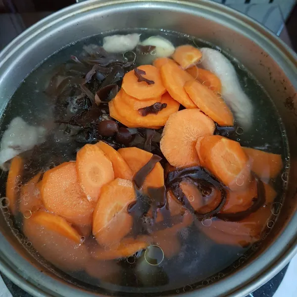 Setelah kuah berkaldu, masukkan potongan wortel dan irisan jamur kuping. Aduk rata dan masak hingga wortel setengah empuk.