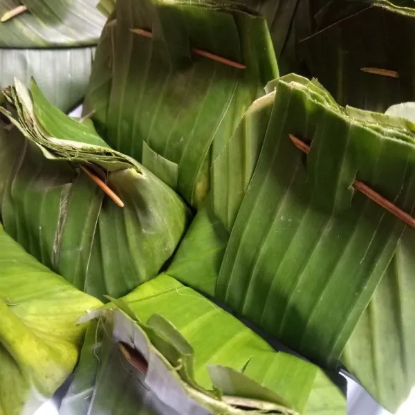 Lalu bungkus dengan daun pisang dan sematkan lidi agar terbungkus rapi.