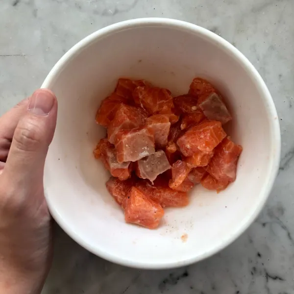 Potong daging salmon berbentuk dadu. Beri sejumput garam, lada, dan gula. Aduk secara merata, kemudian simpan di dalam kulkas 10 menit.