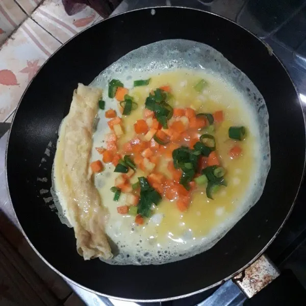 Tuang lagi adonan telur semuanya lalu tambahkan wortel dan daun bawang.