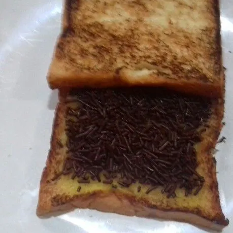 Ambil 2 lembar roti. Taburi 1 sisi dengan meses coklat, tangkupkan dengan lembaran roti satunya.