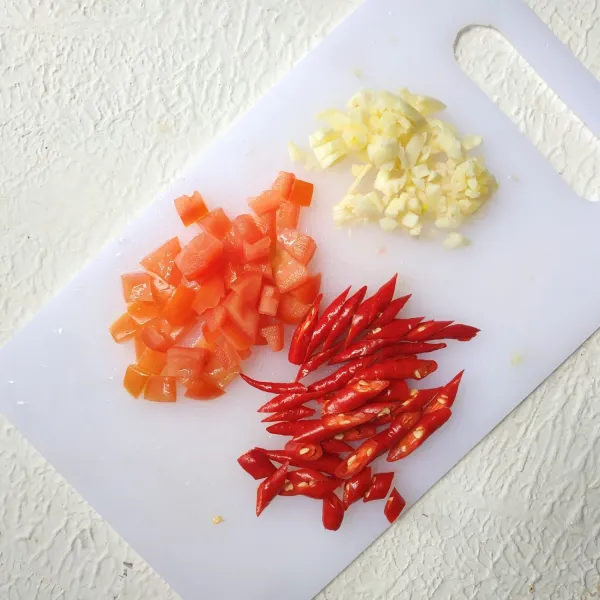 Cincang bawang putih, potong dadu tomat, iris serong cabe.