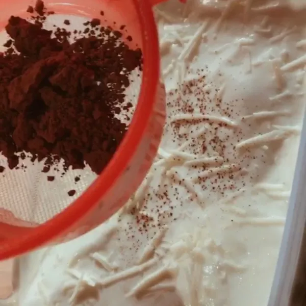 Taburkan cocoa powder diatas layer cream cheese