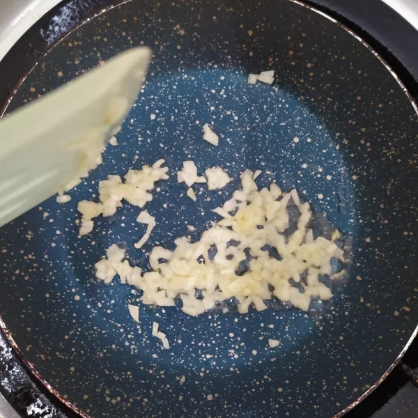 Tumis bawang putih dengan sedikit minyak pada wajan anti lengket sampai kering, lalu simpan untuk taburan