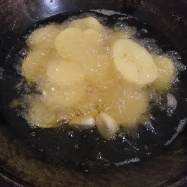 Goreng kentang sampai empuk. Goreng juga bawang putih. Haluskan kentang dan bawang selagi panas.