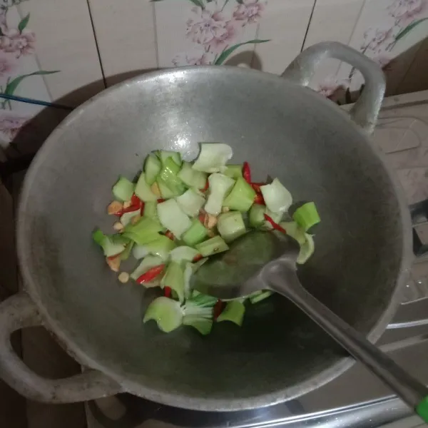 Tumis bawang putih hingga harum lalu masukkan irisan cabai dan batang pokcoy, masak hingga layu