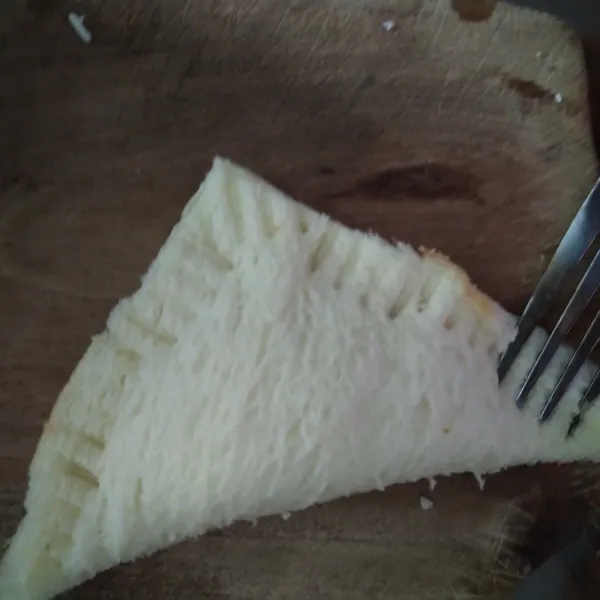 Lipat roti menjadi segitiga, rekatkan antar roti dengan garpu