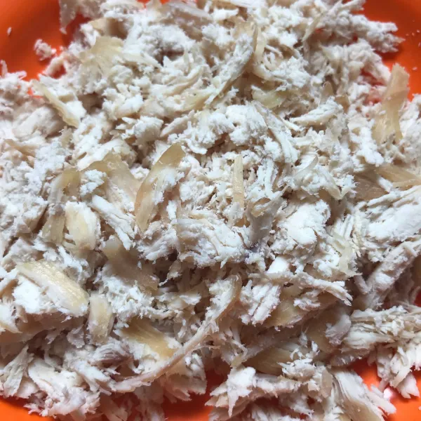 Rebus ayam dada fillet yang sudah dimarinasi dengan bawang putih dan garam hingga matang, kemudian goreng sebentar. Lalu tumbuk kasar/disuwir