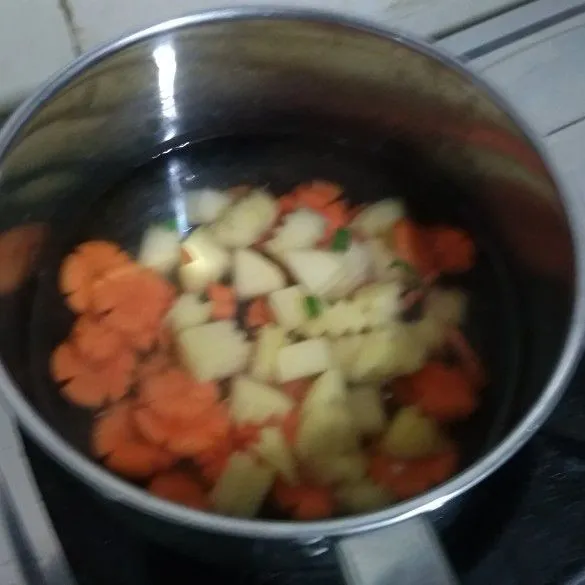 Didihkan air, dan rebus kentang dan wortel