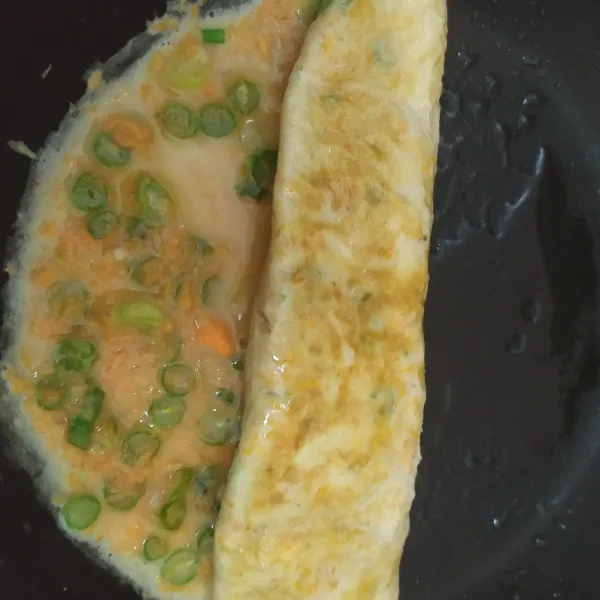 Gulung telur ke salah satu sisi, sisakan bagian ujungnya, geser telur