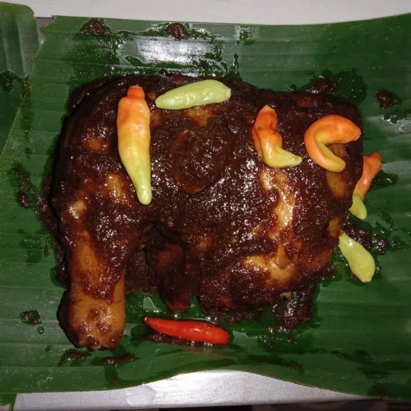 Siapkan loyang yang dialasi dengan daun pisang kemudian pindahkan ayam yang sudah diungkep ke atas loyang, oles ayam menggunakan sisa bumbu ungkep yang masih ada hingga bumbu habis, taburi dengan cabe rawit utuh. Tusuk-tusuk daging ayam menggunakan garpu agar bumbu meresap sempurna saat dipanggang