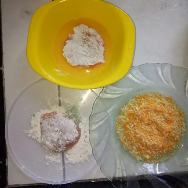 Siapkan 3 wadah yang berbeda untuk tepung terigu, telur kocok lepas dan tepung panir. Setelah selesai marinasi, balur ayam dengan tepung terigu, lalu masukan ke wadah telur, kemudian balur dengan tepung roti sampai tertutup rata, lakukan sampai ayam habis