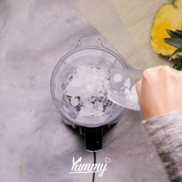 Siapkan blender, masukkan es batu dan buah nanas frozen.