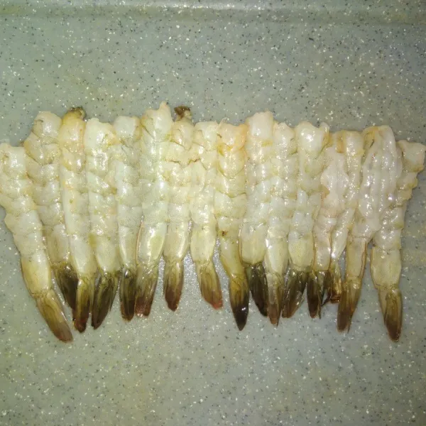 Kupas udang, kerat bagian punggung dan buang kotorannya, kemudian kerat lagi bagian berut agar udang tegak. Kucuri dengan air jeruk nipis diamkan sesaat, bilas. Tiriskan