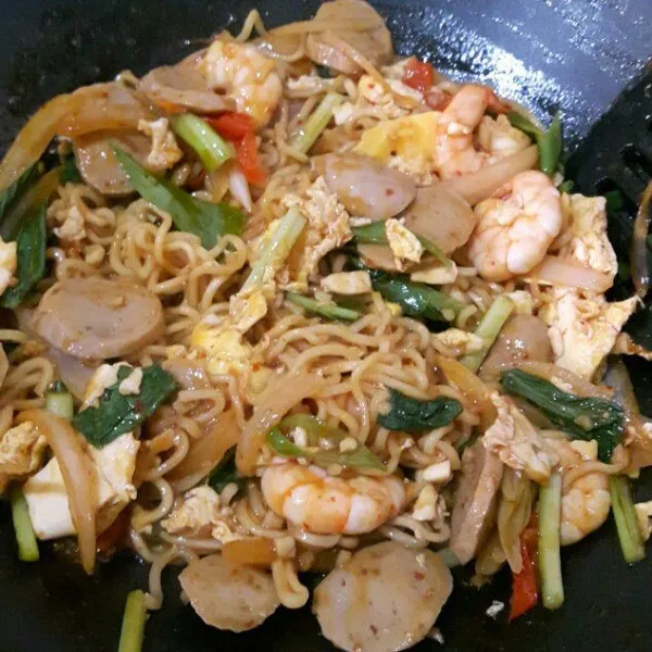 Masukan mie, aduk rata. Masukan potongan caisim dan daun bawang. Aduk rata lagi. Koreksi rasa. Angkat, siap disajikan