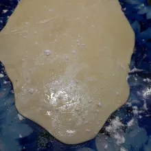 Ambil 1 bulatan, taburi meja kerja dengan tepung, gilas lebar adonan, oles minyak dan taburi tepung