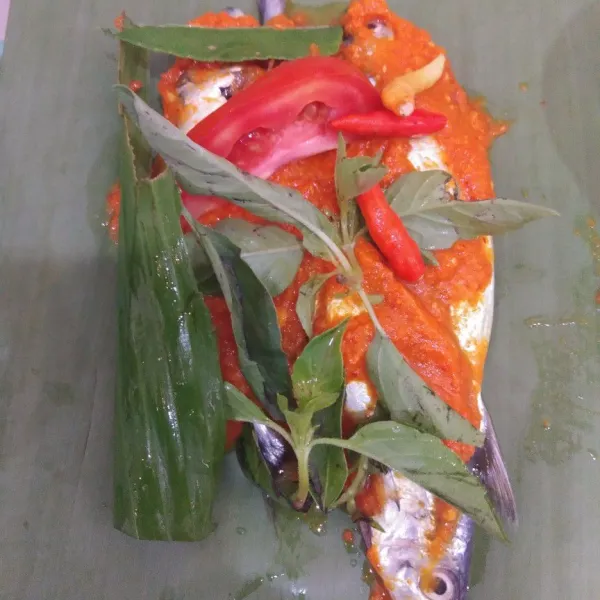 Susun ikan di atas daun, tambahkan bumbu halus, tomat, kemangi,daun jeruk,cabe rawit utuh, dan daun kunyit