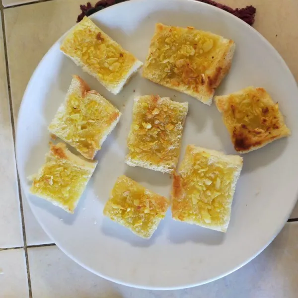 Oleskan campuran margarin-bawang putih di atas roti. Panggang hingga kecoklatan dengan api kecil. Angkat dan sisihkan