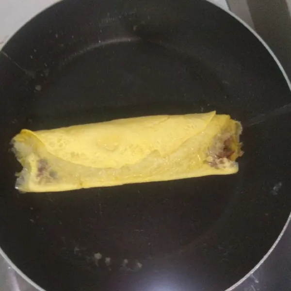 Pinggirkan nasi goreng yang sudah digulung dengan telur, lalu tuang lagi sedikit telur, lakukan hingga sisa telur habis dan nasi goreng tergulung sempurna