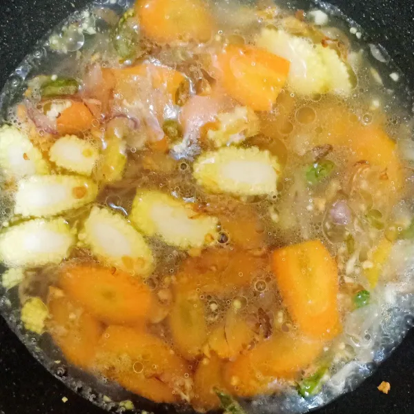 Masukkan jagung muda dan wortel. Tambahkan air. Tunggu sampai wortel matang.
