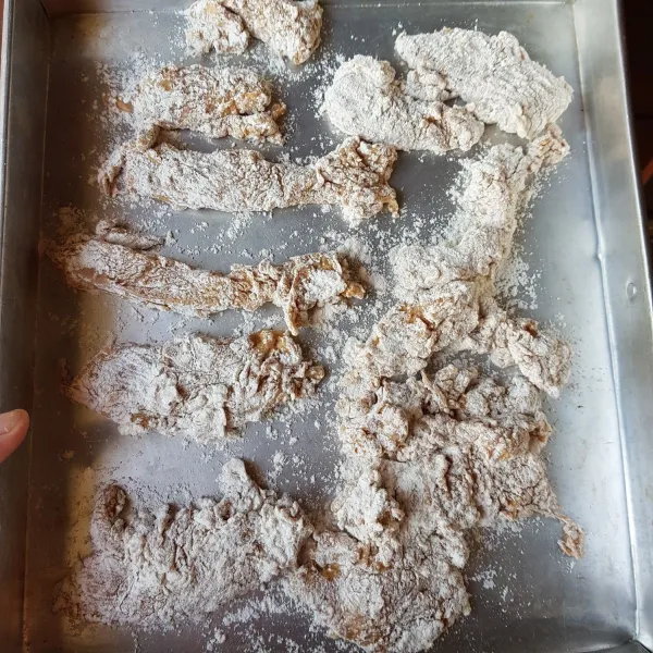 Ambil 1 potong ayam kemudian masukkan ke dalam bahan tepung. Balut ayam dengan tepung hingga rata. Lakukan hingga potongan ayam habis