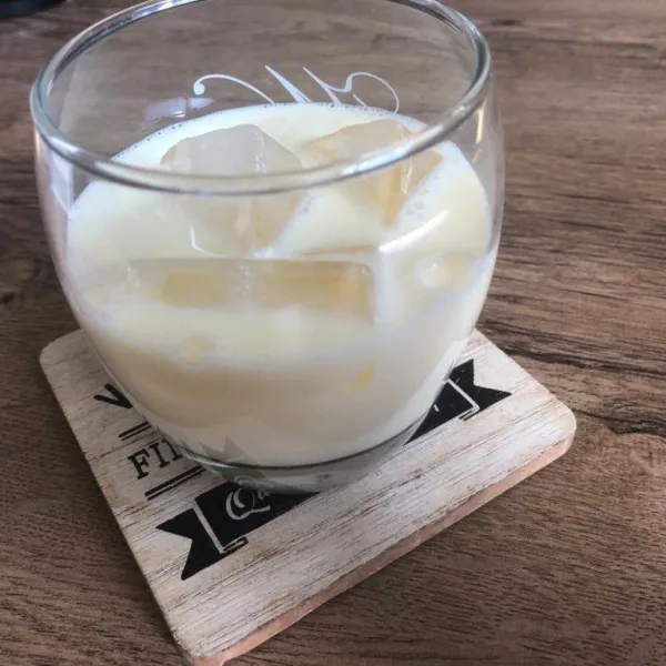 Tuang susu ke dalam gelas yang sudah diisi dengan es.