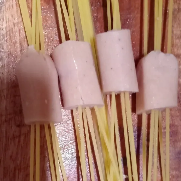 Potong sosis bagi 4, tusukkan spaghetti ke dalam sosis